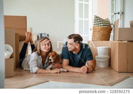New owners are smiling. Young couple with dog are moving to new home New owners are smiling. Young couple with dog are moving to new home 128592273