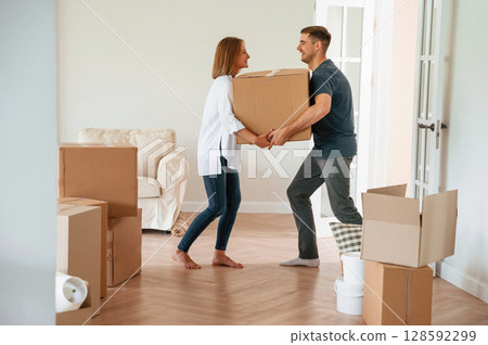 With one heavy box. Young couple moving to new home With one heavy box. Young couple moving to new home 128592299