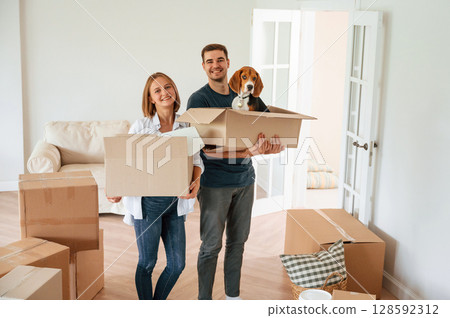 Dog is in the box. Young couple are moving to new home Dog is in the box. Young couple are moving to new home 128592312