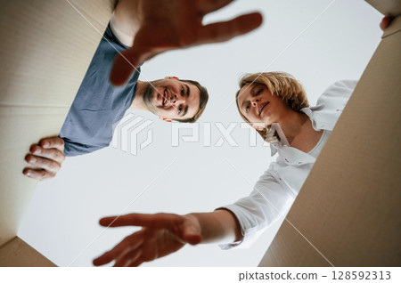 View from the inside of a box. Young couple moving to new home View from the inside of a box. Young couple moving to new home 128592313