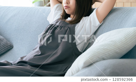 女人坐在客廳的沙發上思考 女人坐在客廳的沙發上思考 128592366