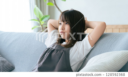 Woman sitting on the sofa in the living room thinking Woman sitting on the sofa in the living room thinking 128592368