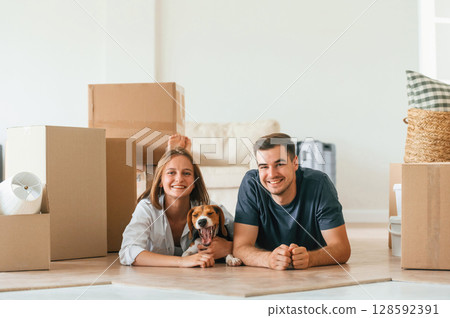 Lying down on the floor. Young couple with dog are moving to new home 128592391