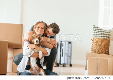Embracing each other. Young couple with dog are moving to new home Embracing each other. Young couple with dog are moving to new home 128592394