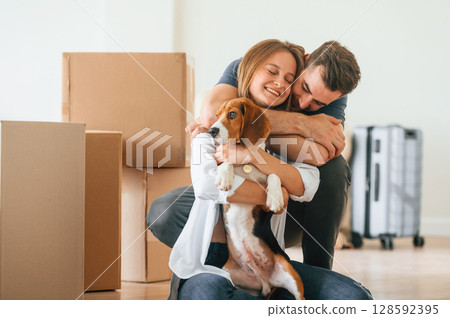 Embracing each other. Young couple with dog are moving to new home 128592395