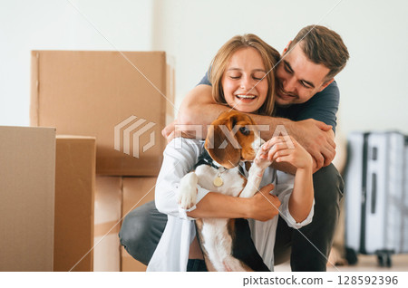 Embracing each other. Young couple with dog are moving to new home Embracing each other. Young couple with dog are moving to new home 128592396