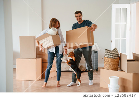 Walking forward with boxes. Young couple with dog are moving to new home 128592417