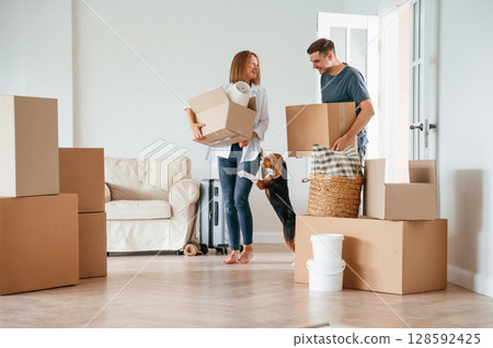 Two boxes in hands. Young couple with dog are moving to new home 128592425