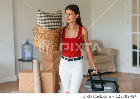 Young woman in casual clothes is moving to new house Young woman in casual clothes is moving to new house 128592484