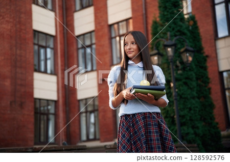In uniform, against building. School girl is outdoors 128592576