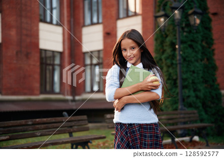 In uniform, against building. School girl is outdoors 128592577