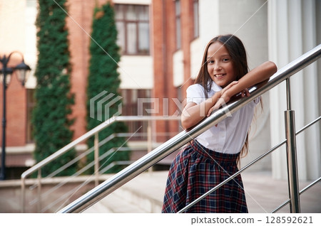 School girl in uniform is outdoors near the building 128592621