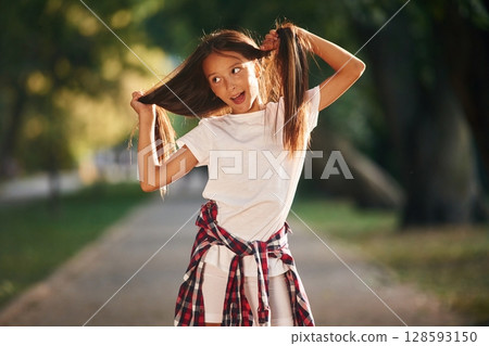 Playful emotions, having fun. Young girl in casual clothes is in the public park outdoors 128593150