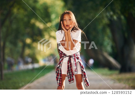 Shocked young girl in casual clothes is in the public park outdoors 128593152