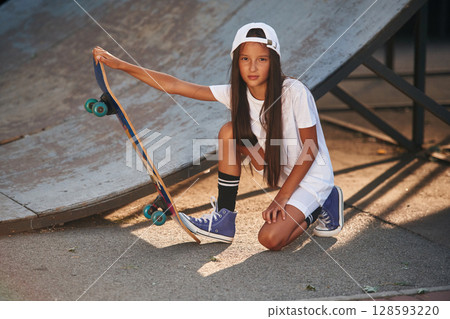 Conception of extreme sports. Happy little girl with skateboard outdoors 128593220