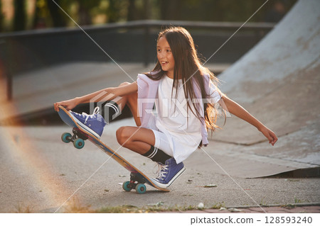 On the ramp. Happy little girl with skateboard outdoors On the ramp. Happy little girl with skateboard outdoors 128593240