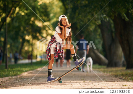 Doing tricks, having fun. Happy little girl with skateboard outdoors 128593268
