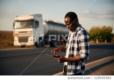 Black man is standing on the road with truck on it 128593363
