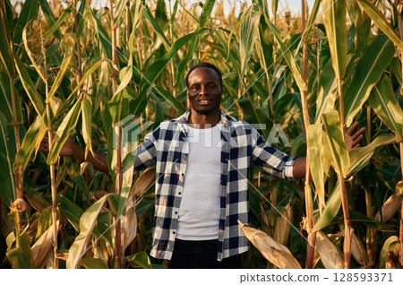 Smiling, positive emotions. Young black man is standing in the cornfield at daytime Smiling, positive emotions. Young black man is standing in the cornfield at daytime 128593371