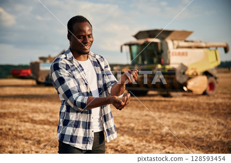 Harvest in hands. Beautiful African American man is in the agricultural field Harvest in hands. Beautiful African American man is in the agricultural field 128593454