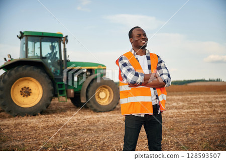 Standing with arms crossed. Beautiful African American man is in the agricultural field 128593507