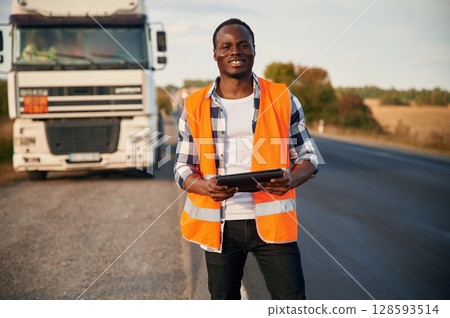 Truck is behind. Black man is standing on the road 128593514