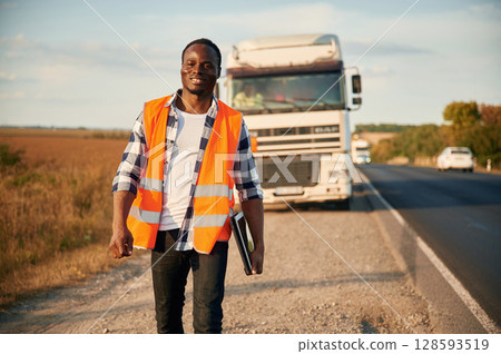 Front view. Black man is standing on the road with truck on it 128593519
