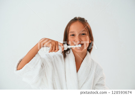 Cleaning the teeth. Conception of beauty and self care. Young girl is in the studio Cleaning the teeth. Conception of beauty and self care. Young girl is in the studio 128593674