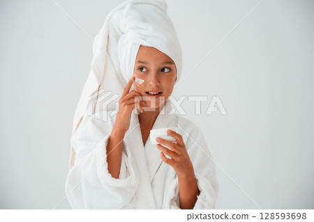 Putting cream on the face. Conception of beauty and self care. Young girl is in the studio 128593698