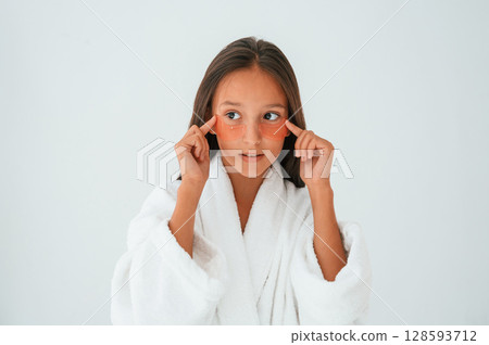 Trying eye patches. Conception of beauty and self care. Young girl is in the studio 128593712