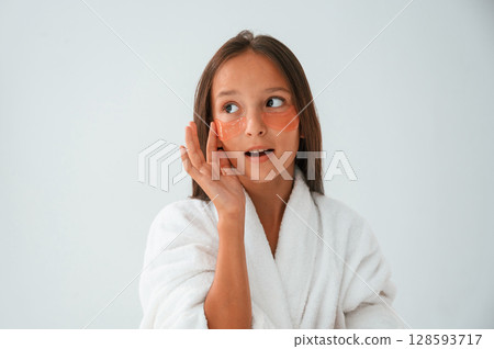With eye patches on the face. Conception of beauty and self care. Young girl is in the studio With eye patches on the face. Conception of beauty and self care. Young girl is in the studio 128593717