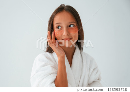 With eye patches on the face. Conception of beauty and self care. Young girl is in the studio 128593718