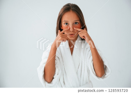 With eye patches on the face. Conception of beauty and self care. Young girl is in the studio With eye patches on the face. Conception of beauty and self care. Young girl is in the studio 128593720