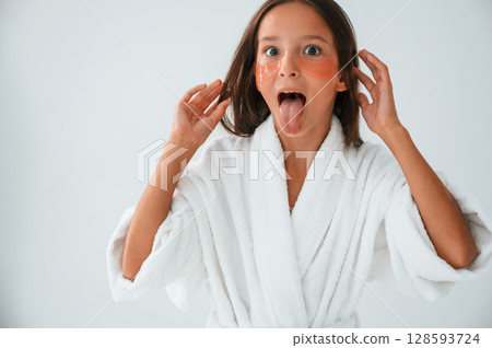 Orange colored eye patches on the face. Conception of beauty and self care. Young girl is in the studio Orange colored eye patches on the face. Conception of beauty and self care. Young girl is in the studio 128593724