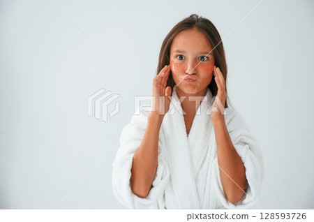 Young girl is in the studio using eye patches on the face Young girl is in the studio using eye patches on the face 128593726
