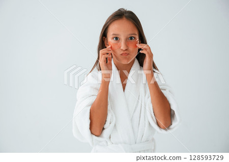 Young girl is in the studio using eye patches on the face Young girl is in the studio using eye patches on the face 128593729