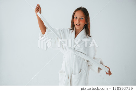 In white robe. Conception of beauty and self care. Young girl is in the studio In white robe. Conception of beauty and self care. Young girl is in the studio 128593739