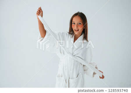 In white robe. Conception of beauty and self care. Young girl is in the studio In white robe. Conception of beauty and self care. Young girl is in the studio 128593740