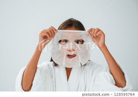 Playing and holding mask for the face. Conception of beauty and self care. Young girl is in the studio 128593764