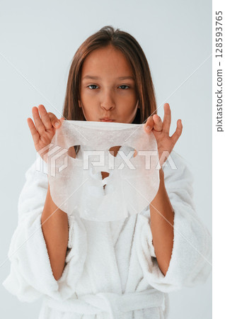 Playing and holding mask for the face. Conception of beauty and self care. Young girl is in the studio 128593765