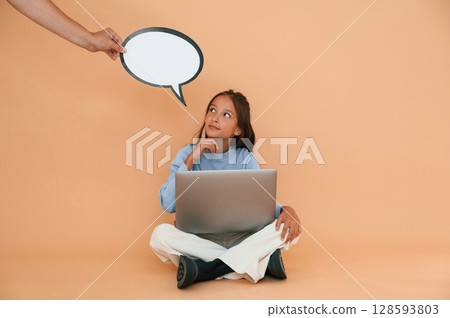 Hand is holding sticker with copy space for text, thoughts. Sitting with laptop. Cute young girl Hand is holding sticker with copy space for text, thoughts. Sitting with laptop. Cute young girl 128593803