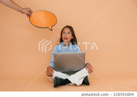 Hand is holding sticker with copy space for text, thoughts. Sitting with laptop. Cute young girl Hand is holding sticker with copy space for text, thoughts. Sitting with laptop. Cute young girl 128593804