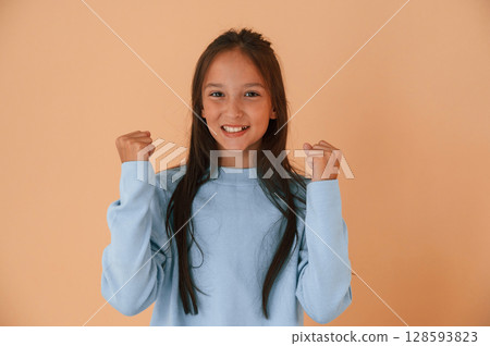 Joyful, celebrating success. Cute young girl is in the studio against background 128593823