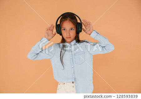 In headphones, positive energy. Cute young girl is in the studio against background In headphones, positive energy. Cute young girl is in the studio against background 128593839