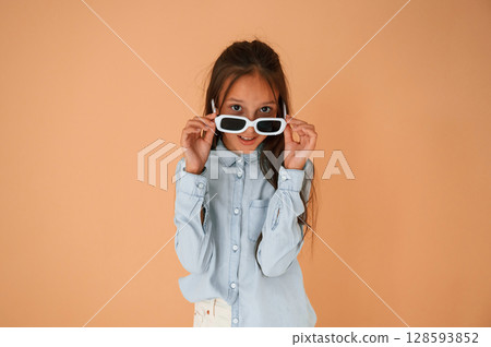Funny facial expression and emotions. In sunglasses. Cute young girl is in the studio against background Funny facial expression and emotions. In sunglasses. Cute young girl is in the studio against background 128593852