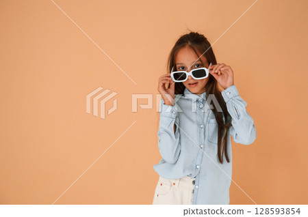 In stylish glasses. Cute young girl is in the studio against background 128593854