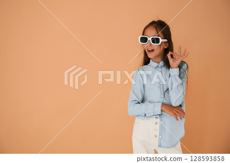 In stylish glasses. Cute young girl is in the studio against background 128593858