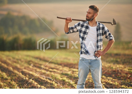 Holding the hoe. Man is on the agricultural field, conception of work and harvest 128594372