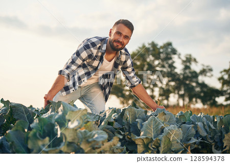 Happy, standing and showing cabbage. Man is on the agricultural field, conception of work and harvest 128594378