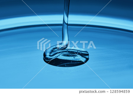 The texture of a cosmetic product in the form of jelly or gel on a blue background. The texture of a cosmetic product in the form of jelly or gel on a blue background. 128594859